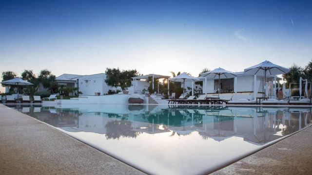 Infinity-Pool im Sonnenuntergang mit stilvoller Architektur im Hintergrund.