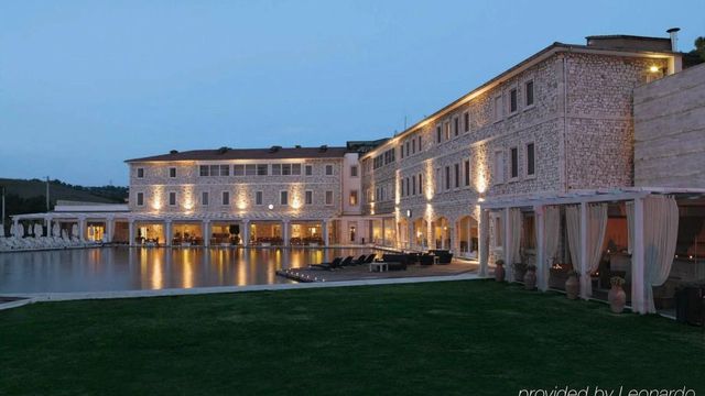 Hotelgebäude bei Dämmerung mit beleuchtetem Pool und Garten