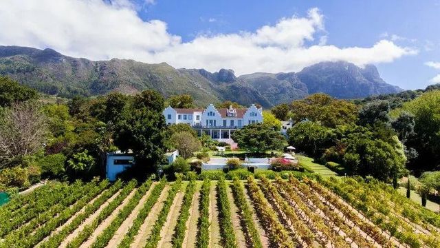 Historische Fassade des Hotels umgeben von Weinbergen und Bergen im Hintergrund
