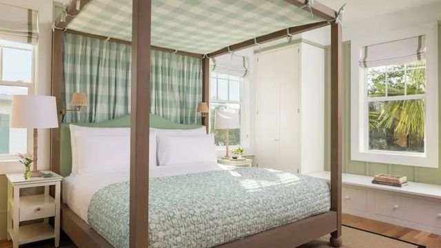 Helles Schlafzimmer mit Himmelbett und karierten Vorhängen