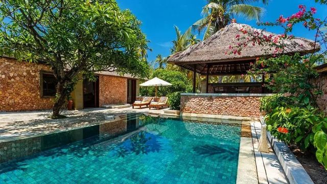 Privater Pool mit Liegestühlen und tropischem Garten im Oberoi Beach Resort Lombok