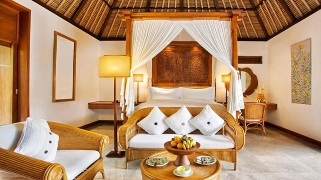 Luxuriöse Suite mit Baldachinbett und gemütlichem Sitzbereich in balinesischem Design