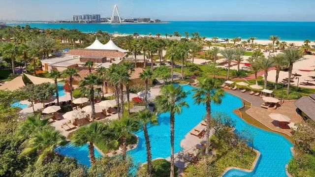 Poollandschaft mit Palmen und Blick auf den Strand sowie das Meer in Dubai