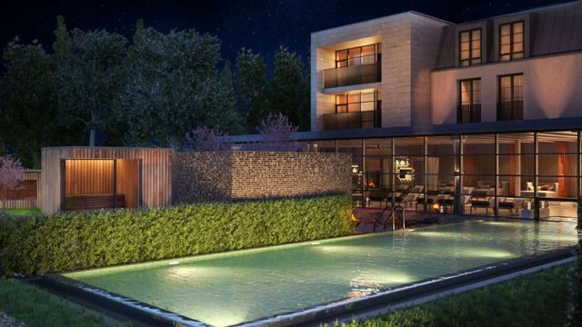 Beleuchteter Pool bei Nacht vor moderner Architektur und grüner Hecke