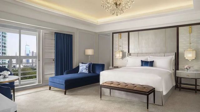 Elegantes Hotelzimmer mit Doppelbett, blauer Chaiselongue und Kronleuchter