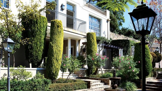 Elegante Hotelfassade mit gepflegtem Garten und hohen Bäumen