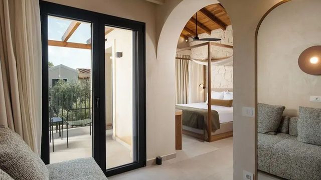 Blick vom Balkon mit Sitzbereich ins Schlafzimmer mit offenem Dachbalken.