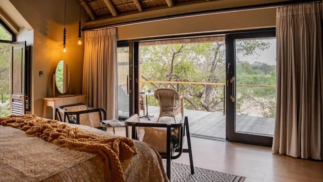 Zimmer mit großen Fenstern und direktem Zugang zur Terrasse mit Naturblick