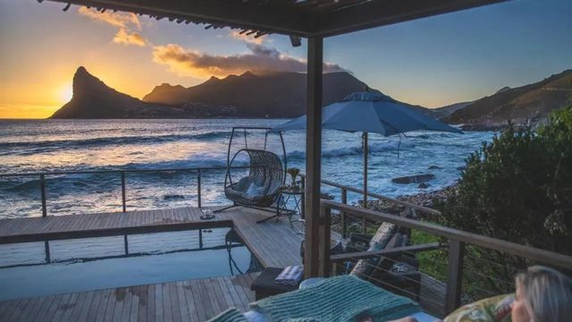 Privater Pool mit Meerblick in der Abenddämmerung, Hängesessel auf der Terrasse.