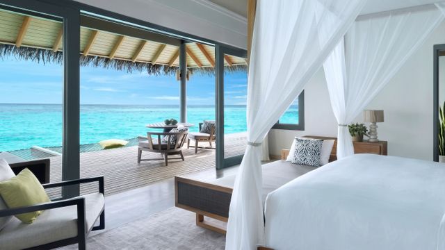 Villa mit Doppelbett und Meerblick durch große Glasfront auf Malediven