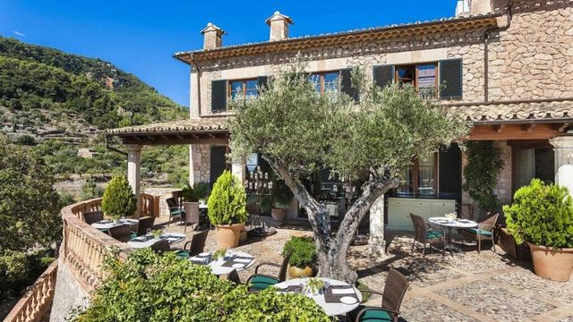 Mediterrane Terrasse mit Olivenbaum und Sitzgelegenheiten vor Steinfassade