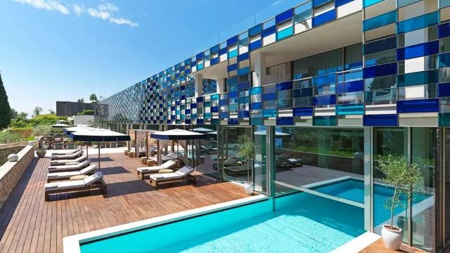 Moderner Außenbereich mit Pool und stilvollen Liegen neben einem innovativen Gebäude mit blauen Akzenten