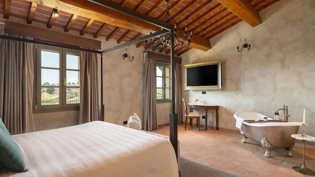 Schlafzimmer mit Himmelbett und großem Fenster im Villa Petriolo Hotel