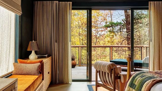 Gemütliches Zimmer mit Zugang zu einem Balkon mit Waldsicht im Herbst