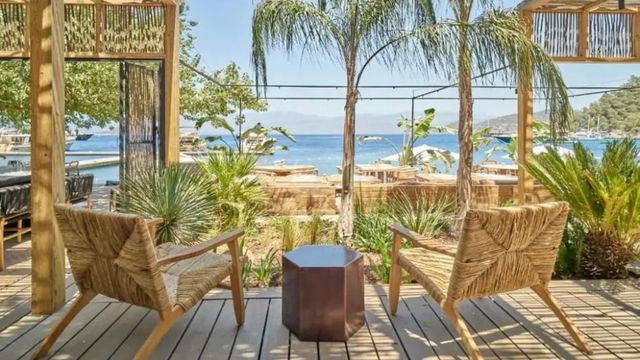 Terrasse mit zwei Stühlen und Blick auf das Meer durch Palmen