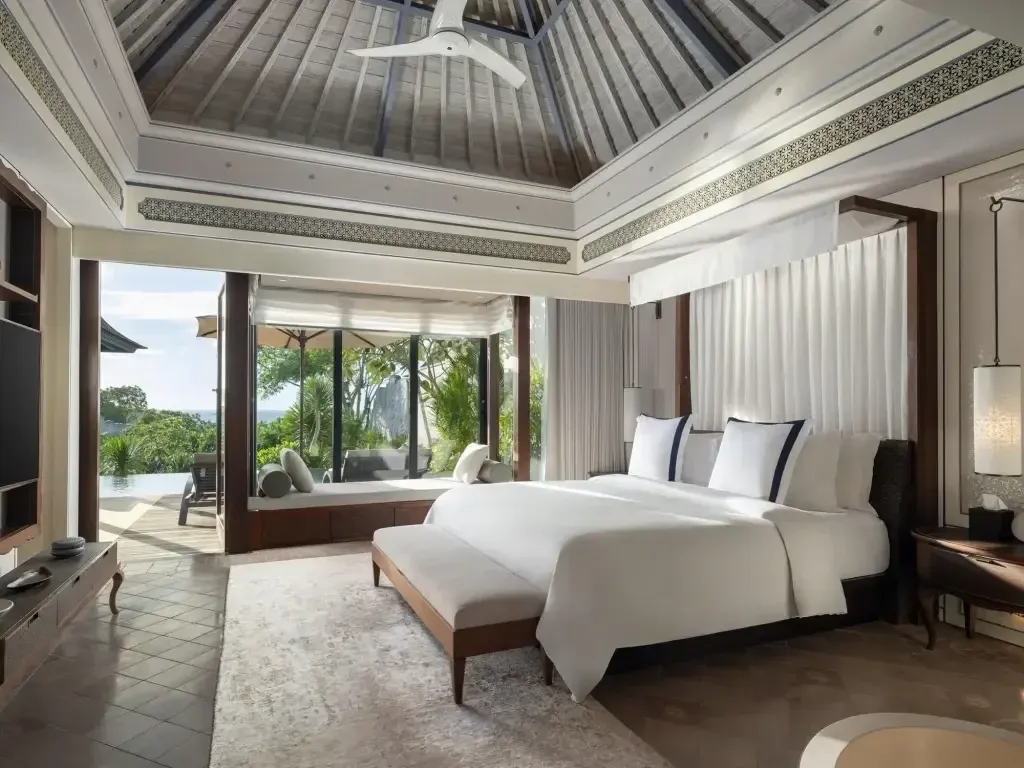 Luxuriöses Schlafzimmer mit großem Bett und Blick auf den Garten durch große Fenster