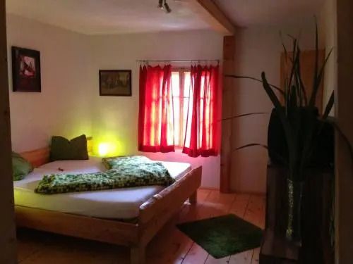 Gemütliches Schlafzimmer mit Holzbett, roten Vorhängen und Pflanzenakzenten