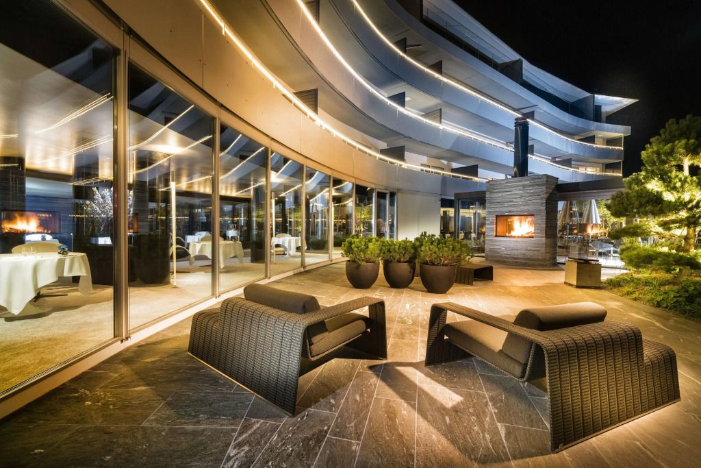 Luxuriöse Terrasse mit modernen Sitzgelegenheiten und offenem Kamin bei Nacht