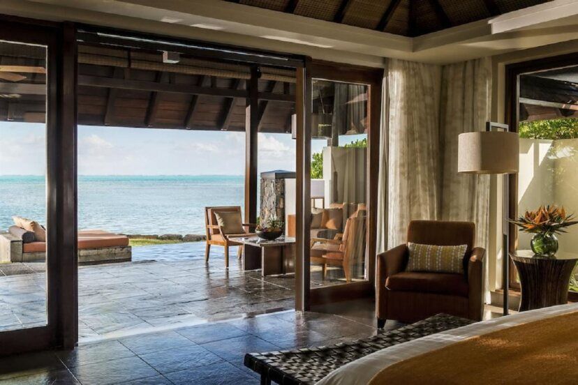 Blick aus einer luxuriösen Villa des Four Seasons Resort Mauritius at Anahita auf eine private Terrasse mit Sitzbereich und Blick auf den türkisblauen Indischen Ozean.