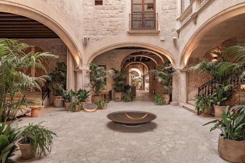 Historischer Innenhof des Nobis Hotel Palma mit Sandsteinbögen, antiken Mauern, mediterranen Pflanzen und stilvoller Beleuchtung – eine Mischung aus mallorquinischer Tradition und modernem Design.