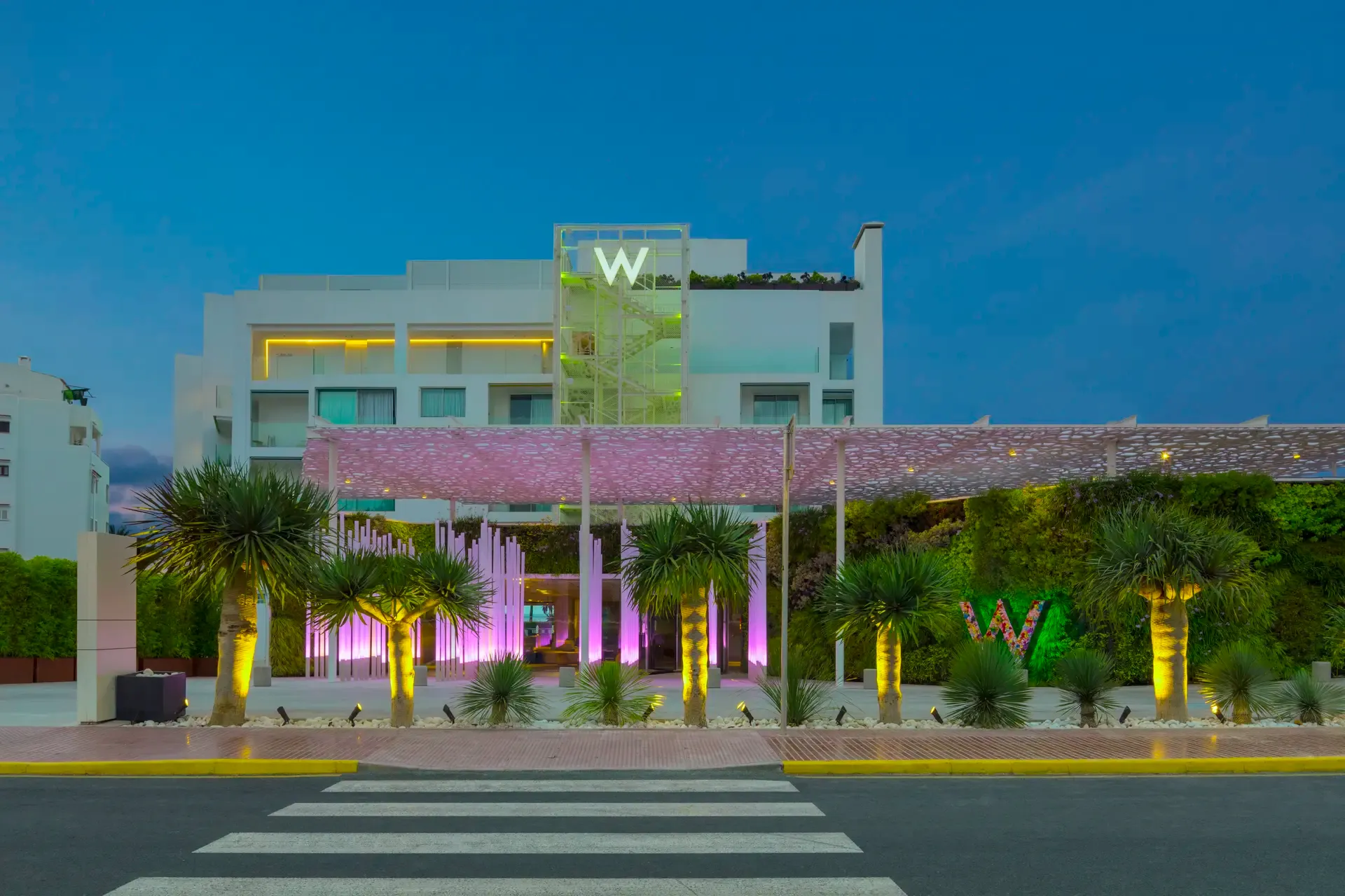 Stylischer Hoteleingang des W Ibiza mit moderner Architektur, farbenfroher LED-Beleuchtung und tropischem Flair inmitten der Stadt.