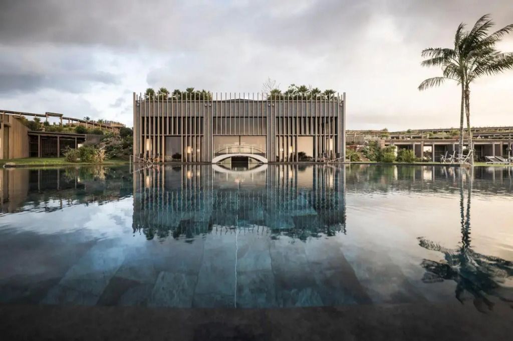 Moderner Pool mit reflektierendem Wasser vor einem imposanten Gebäude im Hotelresort