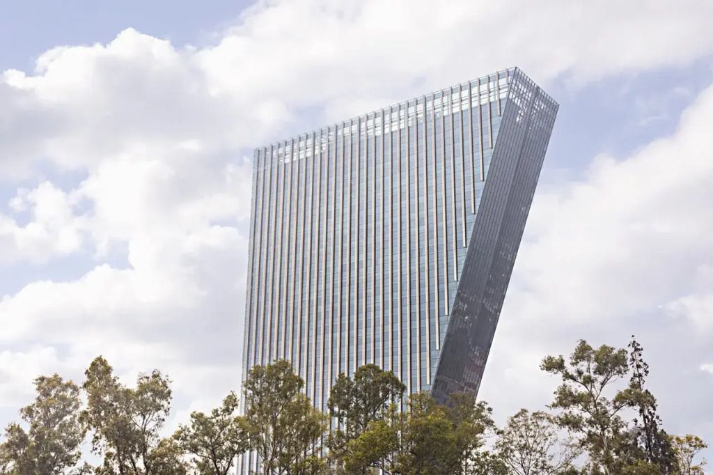 Modernes Hochhaus mit einzigartiger Architektur und grünen Bäumen im Vordergrund