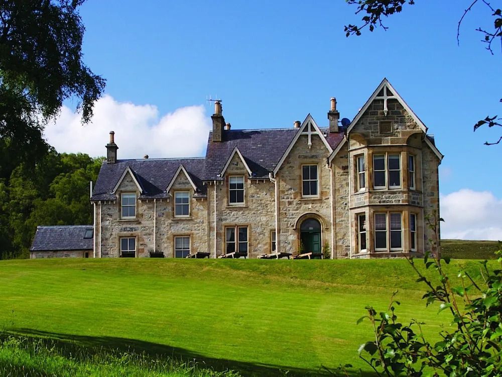 Historische Fassade des Alladale Wilderness Reserve umgeben von grüner Landschaft