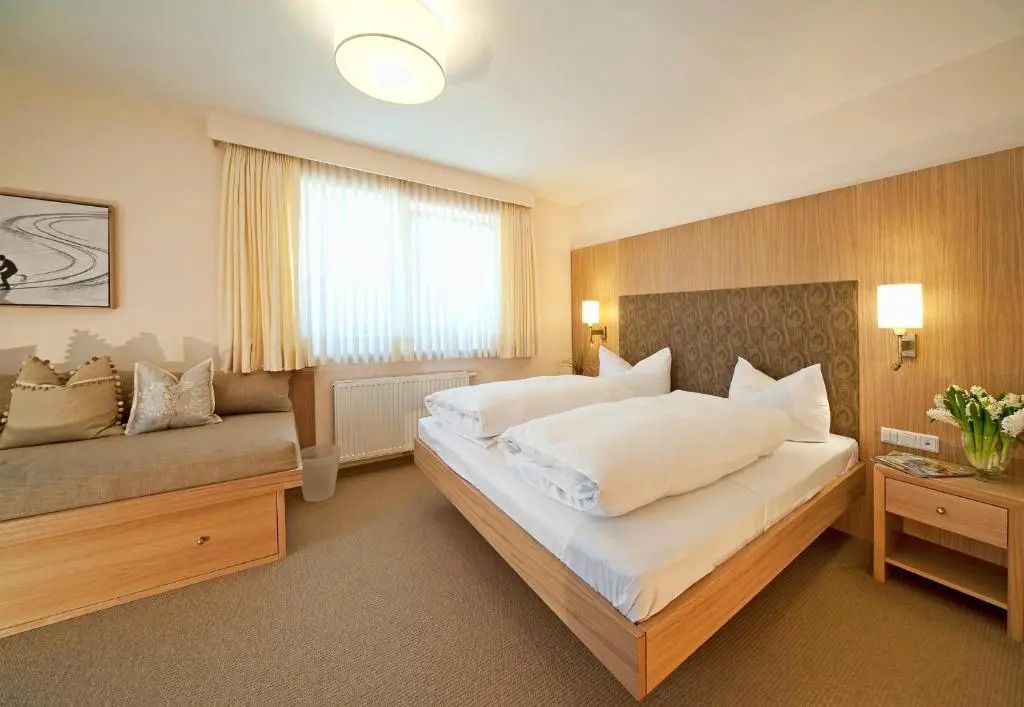 Helles Hotelzimmer mit Doppelbett und großem Fenster