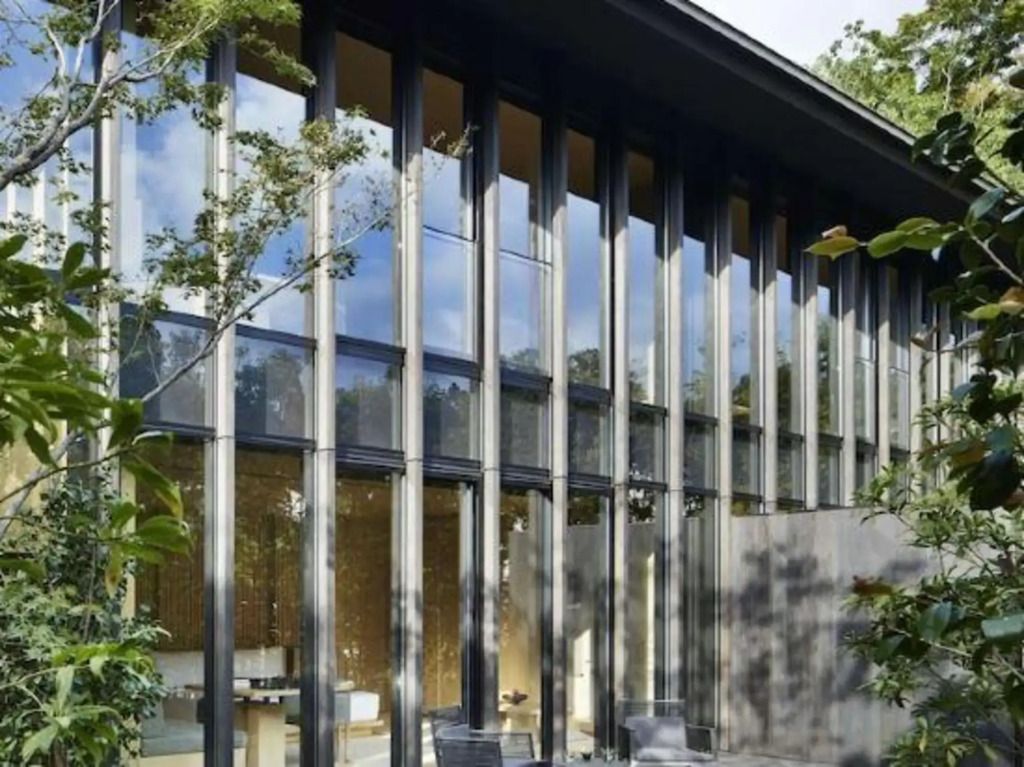 Moderne Fassadenarchitektur mit hohen Fenstern und umgebendem Grün bei Aman Kyoto