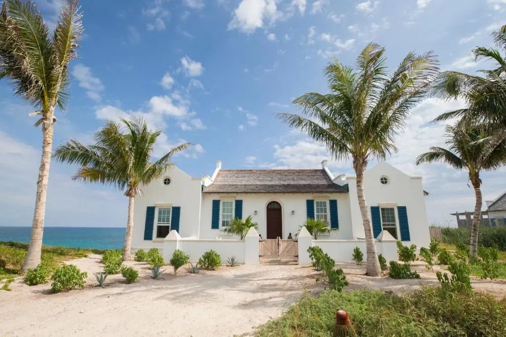 Strandvilla mit Palmen und Blick auf das Meer bei sonnigem Wetter
