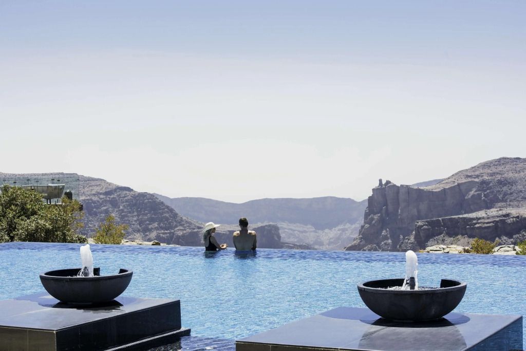 Paar im Infinity-Pool mit Blick auf spektakuläre Berglandschaft