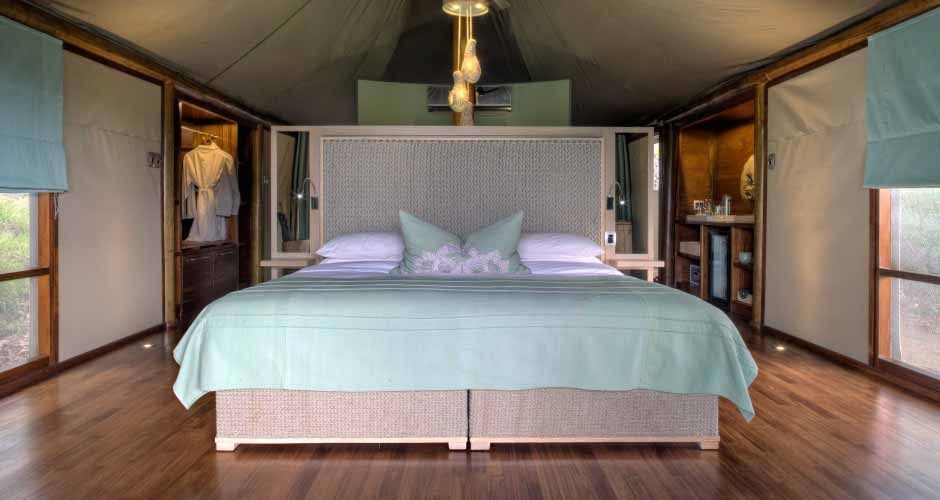 Luxuriöses Zeltzimmer mit großem Bett und sanften Grüntönen im AndBeyond Ngala Tented Camp.