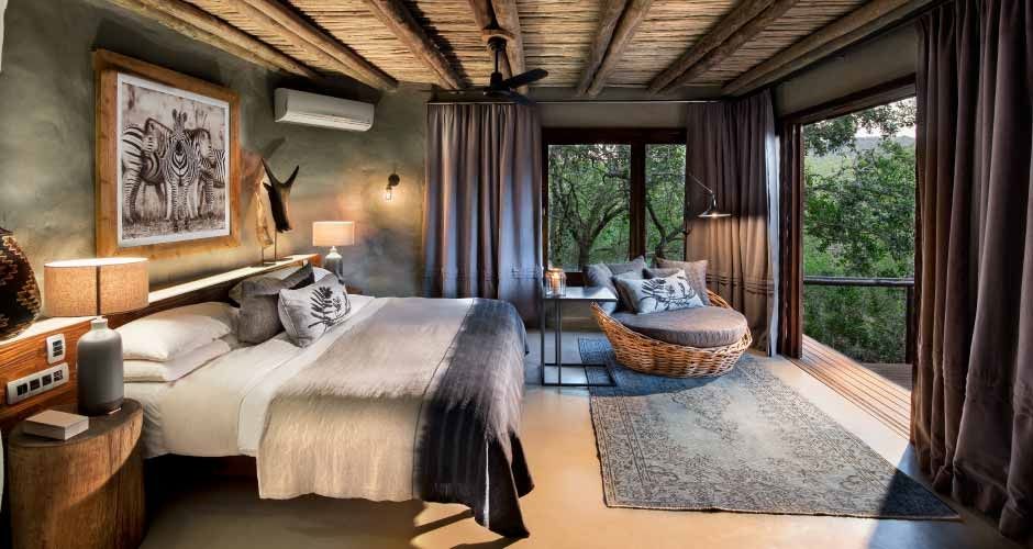 Luxuriöses Schlafzimmer in Safari-Lodge mit Holzbalkendecke und Panoramablick.