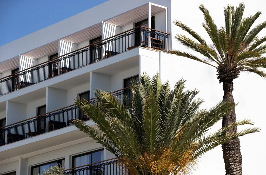 Moderne Hotelfassade mit Balkonen und Palmen im Vordergrund