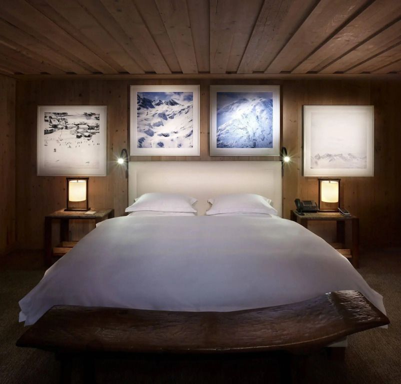 Luxuriöses Schlafzimmer mit Kunstwerken über dem Bett und Holzakzenten