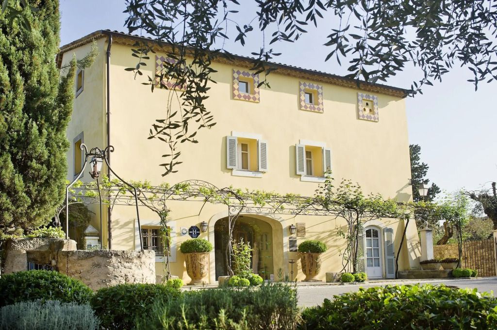 Charmante Fassade eines historischen Gebäudes mit Efeu-Überdachung in provenzalischer Landschaft.