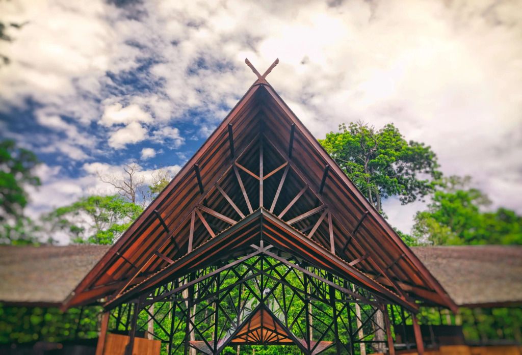 Einzigartige Holzkonstruktion mit dreieckigem Giebel vor tropischem Himmel