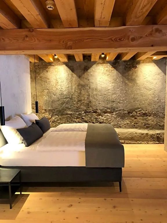 Modernes Hotelzimmer mit Natursteinwand und Holzbalkendecke