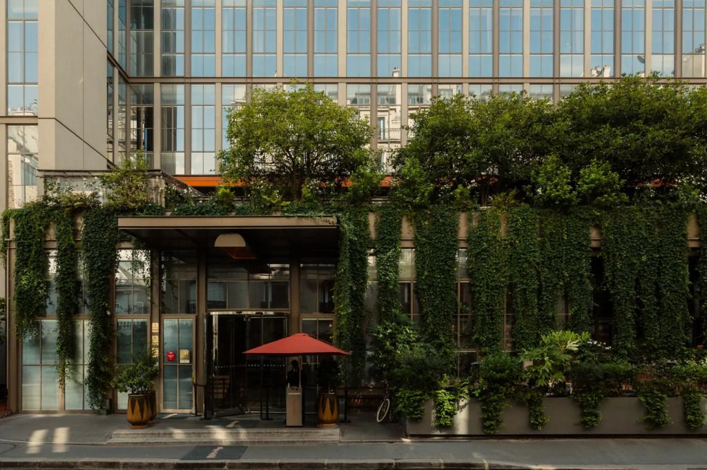 Grüne Fassade des Hotels Brach Paris mit üppiger Vegetation und großen Fenstern