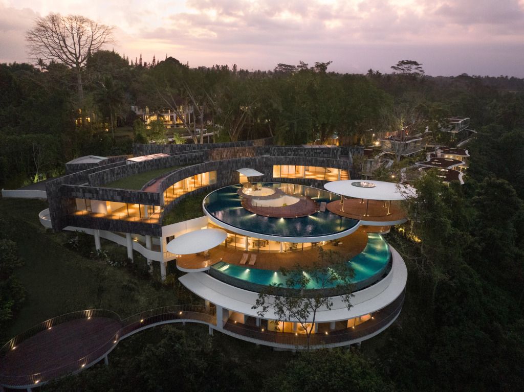 Modernes Gebäude mit geschwungener Architektur im Grünen bei Sonnenuntergang