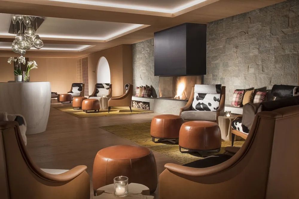 Lounge mit gemütlichen Sesseln und Kamin im alpinen Stil