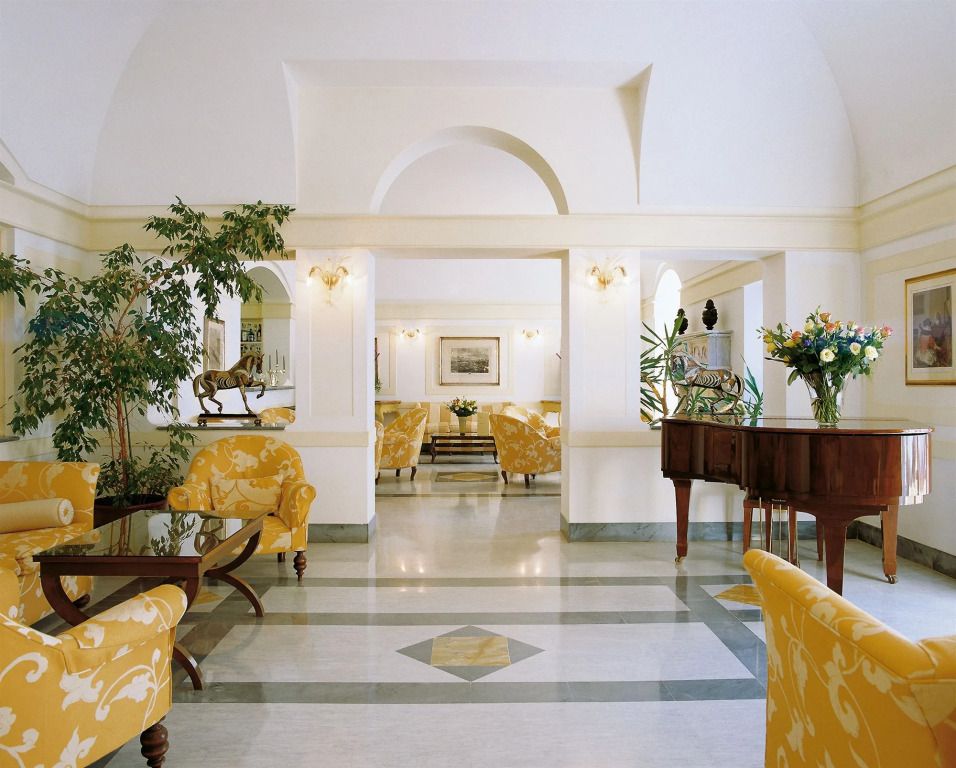 Elegante Lobby mit gelben Sesseln und Pflanzen im Hotel Byron