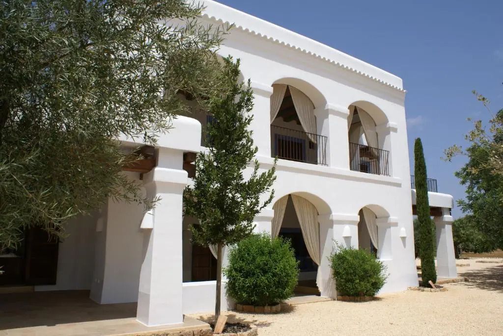 Weißes Gebäude mit Arkaden und Bäumen im mediterranen Stil