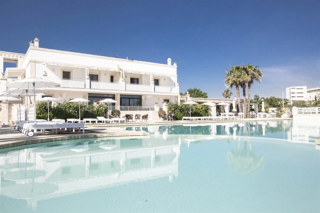 Außenansicht des Canne Bianche Lifestyle Hotels mit Pool und Palmen.