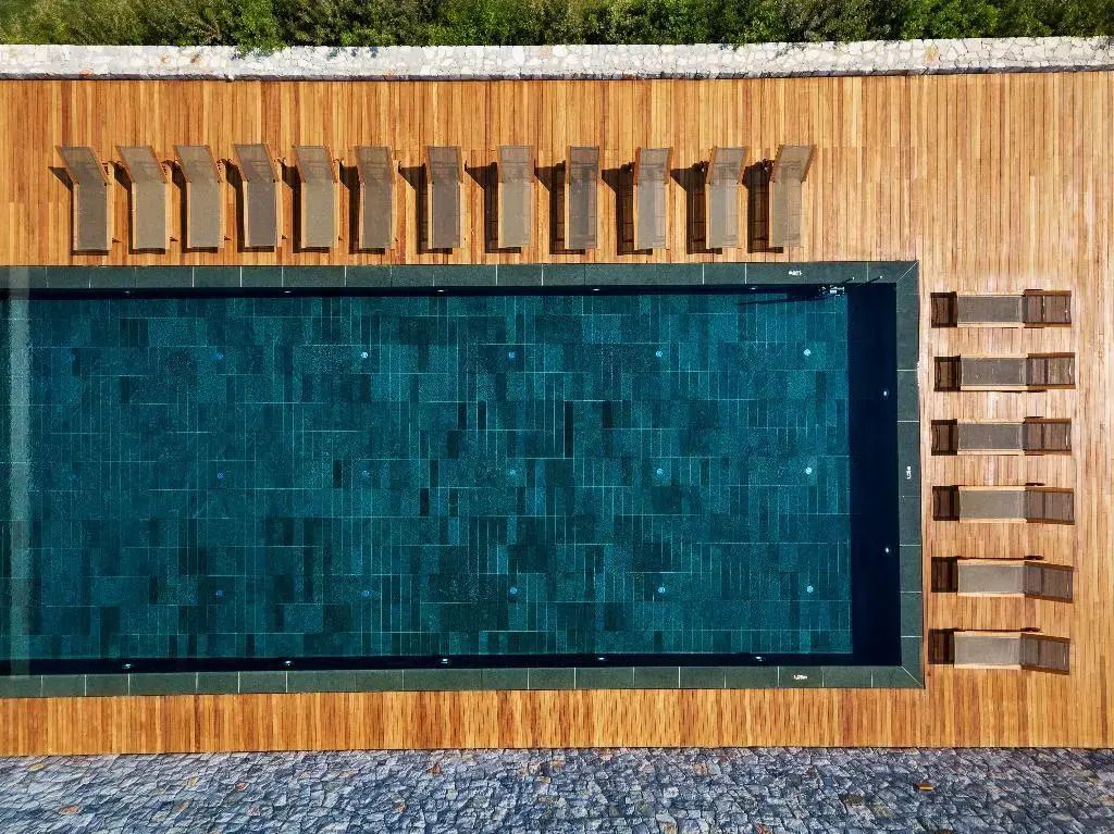 Drohnenaufnahme eines luxuriösen Pools mit Liegestühlen im modernen Design