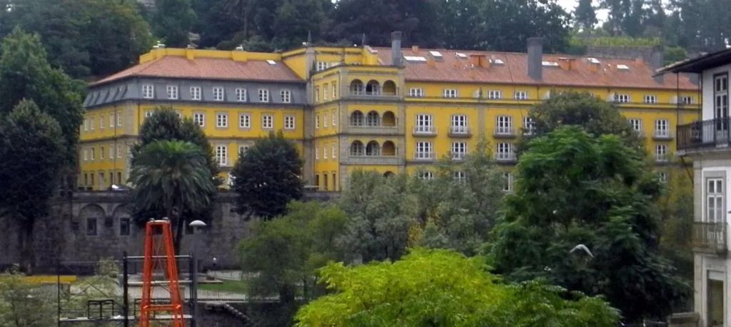 Charmante historische Fassade eines gelben Gebäudes inmitten grüner Bäume