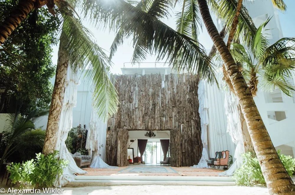 Eingangsbereich des Hotels mit Palmen und rustikaler Holzwand