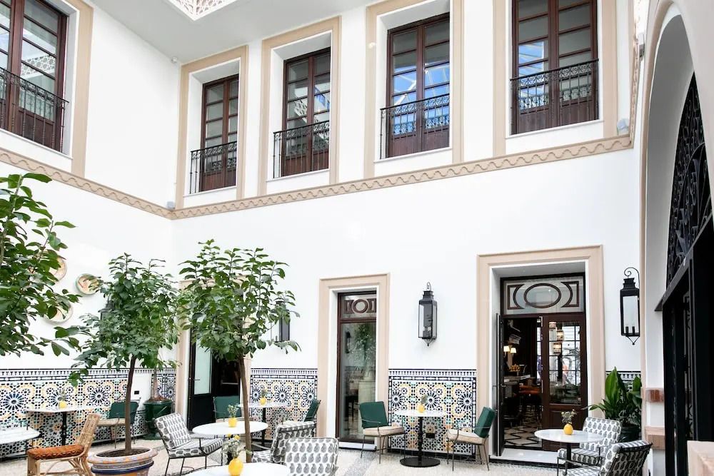 Eleganter Innenhof mit Tischen, Stühlen und traditionellen Fliesen.