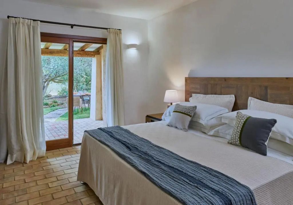 Helles Hotelzimmer mit Doppelbett und Blick auf einen privaten Garten